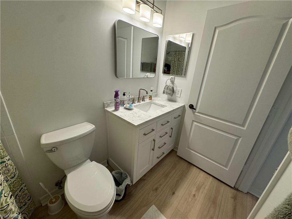 Bathroom with toilet, vanity, and hardwood / wood-style floors