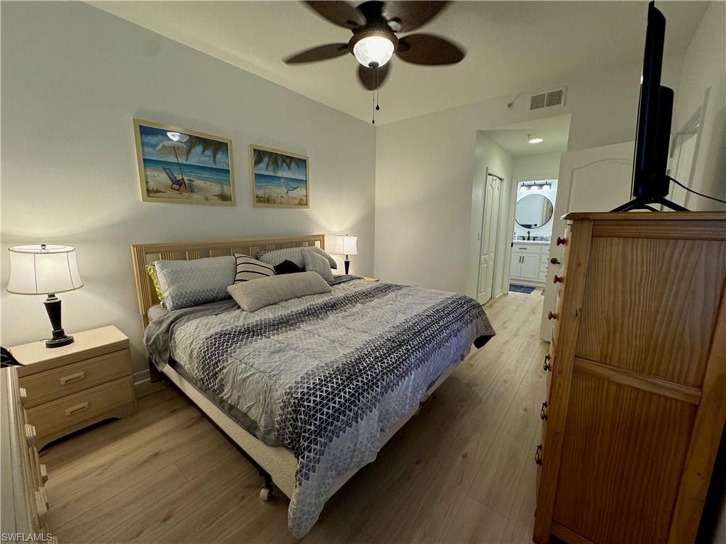 Bedroom with light wood-type flooring, ensuite bath, ceiling fan, and a closet