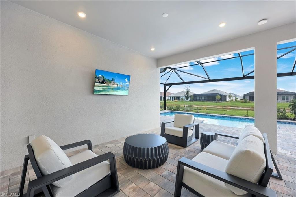 View of patio / terrace featuring a sunroom, outdoor lounge area, ceiling fan, an outdoor pool, and a lanai