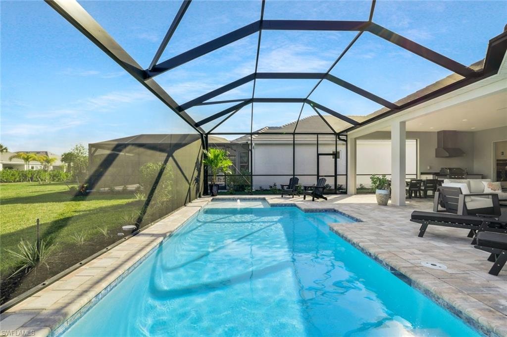Outdoor pool featuring a sunroom, a patio, glass enclosure, a lawn, and a residential view