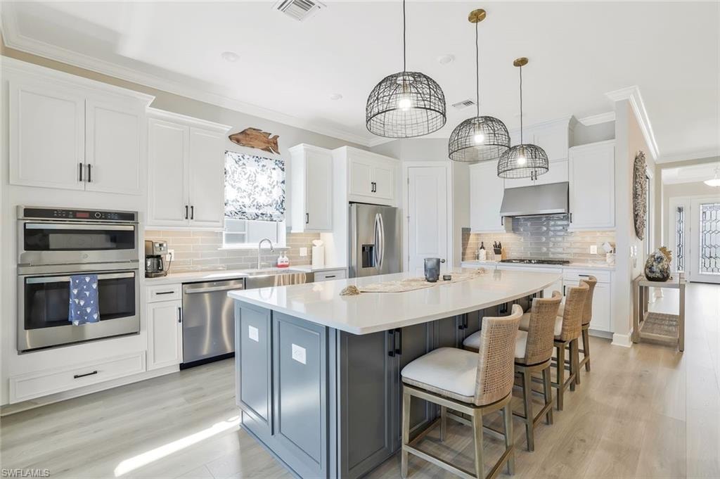 Kitchen featuring white cabinets, ornamental molding, a kitchen island, and a breakfast bar area