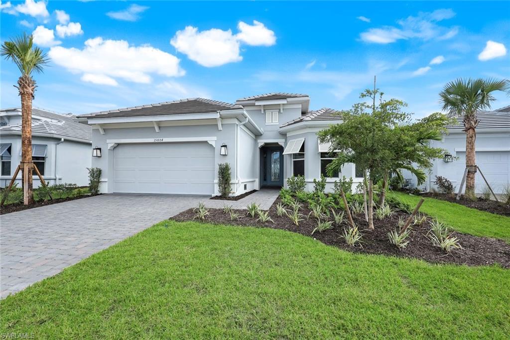 View of front of home with decorative driveway, stucco siding, and a front yard