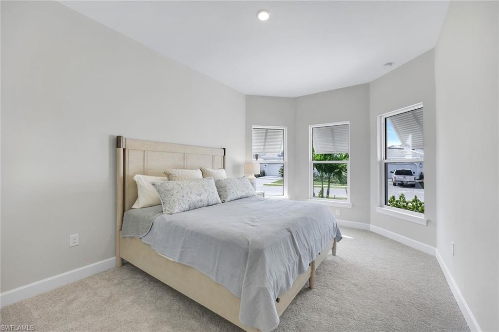 Bedroom with light colored carpet and baseboards