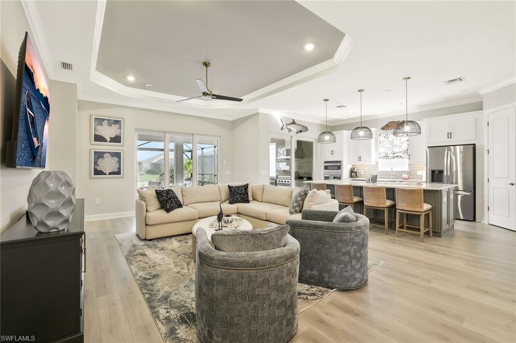 Living room featuring light wood-style floors, crown molding, a ceiling fan, and recessed lighting