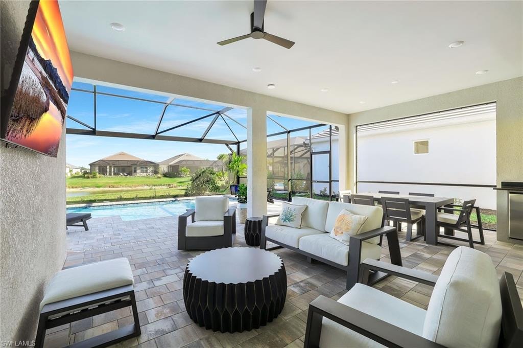Outdoor pool featuring a sunroom, a patio area, glass enclosure, a lawn, and grilling area