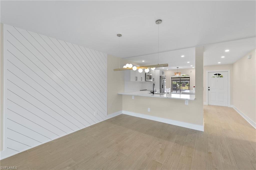 Kitchen with a kitchen breakfast bar, pendant lighting, light wood finished floors, recessed lighting, and a peninsula