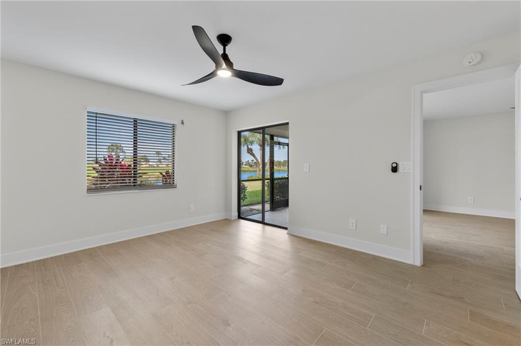 Empty room featuring light wood-type flooring, a ceiling fan, and a water view