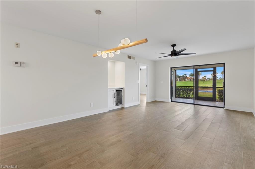 Unfurnished living room with light wood-type flooring, ceiling fan, and beverage cooler