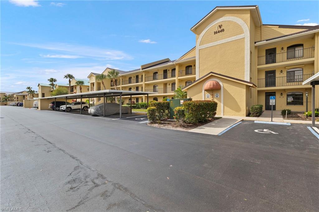 View of apartment building / complex featuring covered and uncovered parking