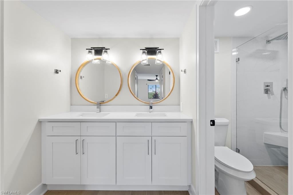 Bathroom featuring double vanity, a shower stall, and light wood-type flooring