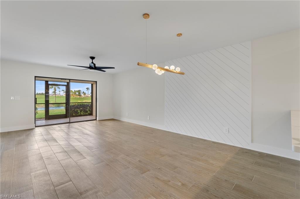 Unfurnished room featuring light wood-type flooring, ceiling fan, a chandelier, and a water view