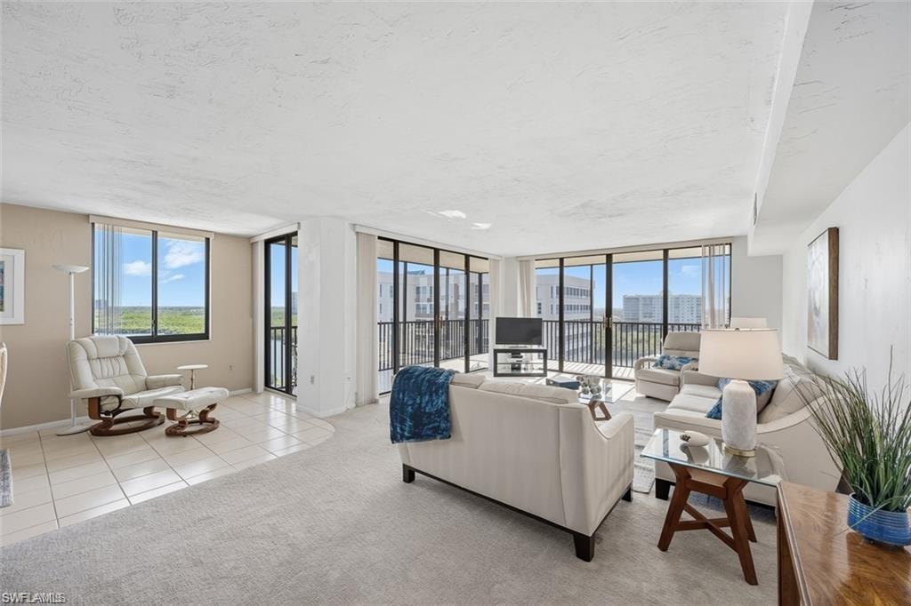 Carpeted living room with tile patterned flooring, a textured ceiling, and floor to ceiling windows