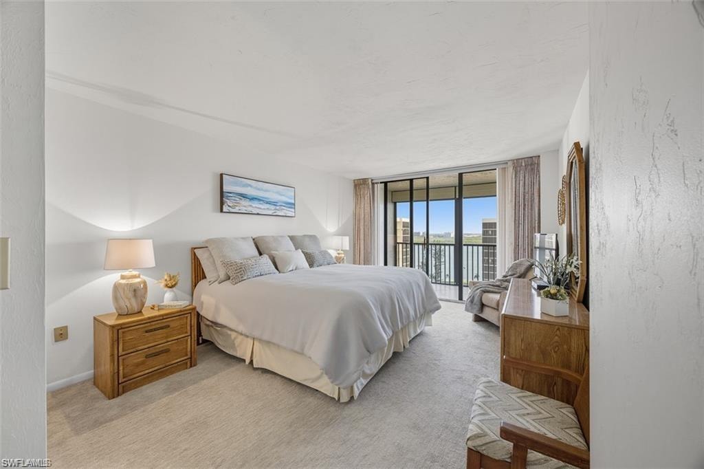 Bedroom with access to exterior, carpet, expansive windows, and a textured wall