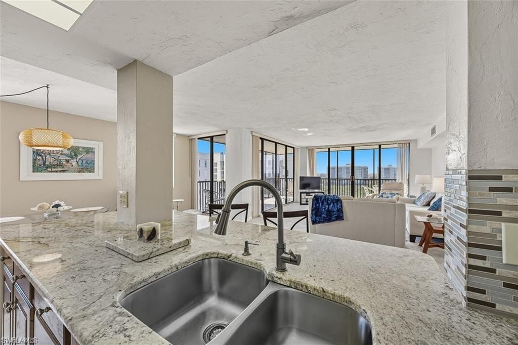 Kitchen with light stone countertops, decorative light fixtures, and open floor plan