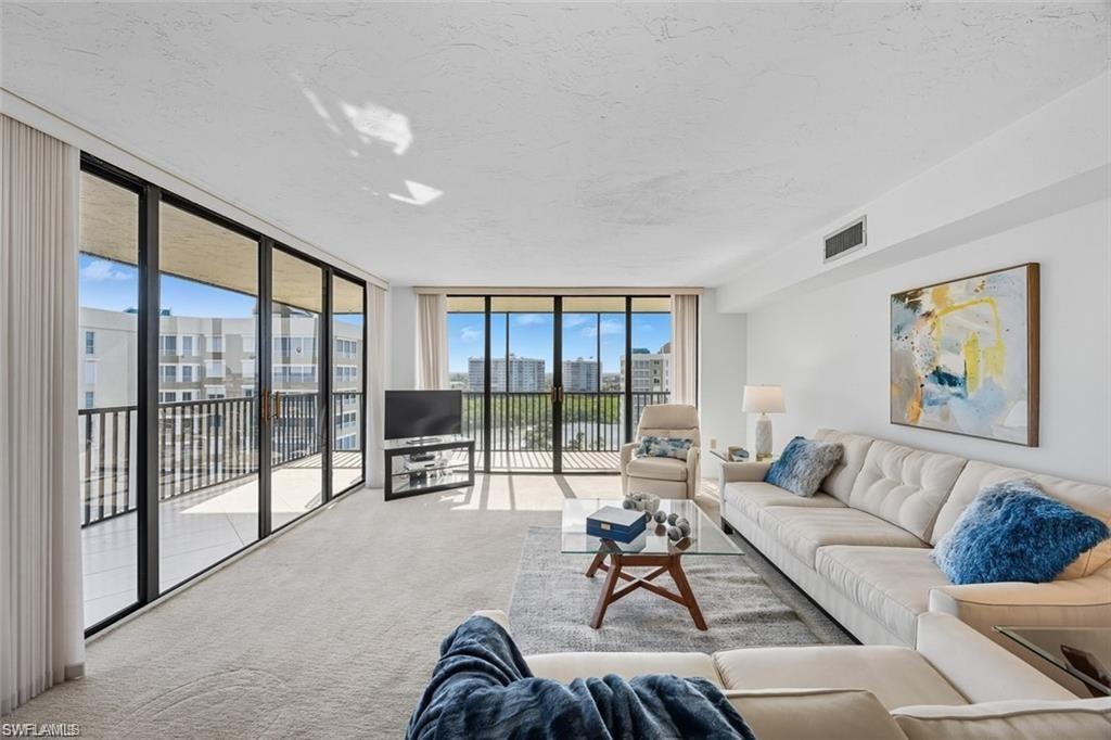 Carpeted living area featuring expansive windows and a textured ceiling