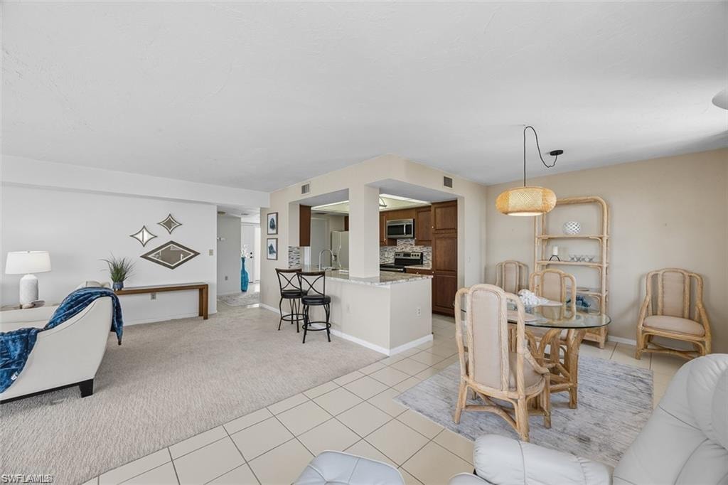Dining space featuring light colored carpet and light tile patterned floors