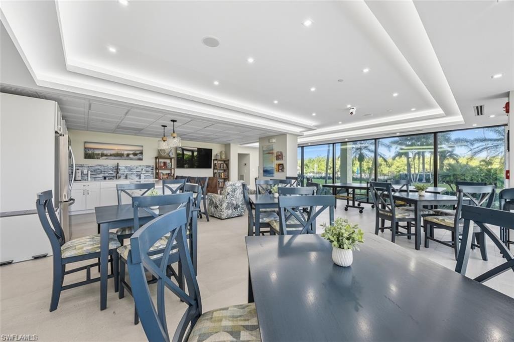 Lobby Dining room with a raised ceiling, a wall of windows, and recessed lighting
