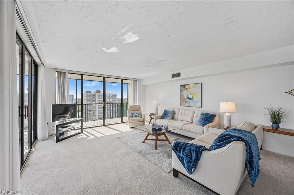 Living room with floor to ceiling windows, carpet flooring, and a textured ceiling