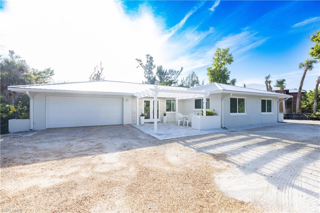 Ranch-style home with a pergola, a patio area, dirt driveway, and a garage
