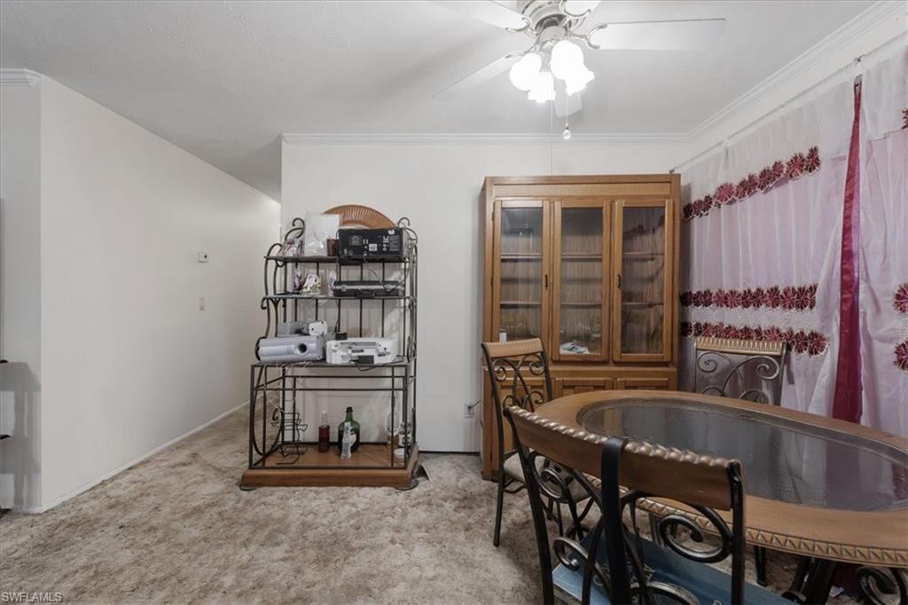 Dining area with light colored carpet, crown molding, and a ceiling fan
