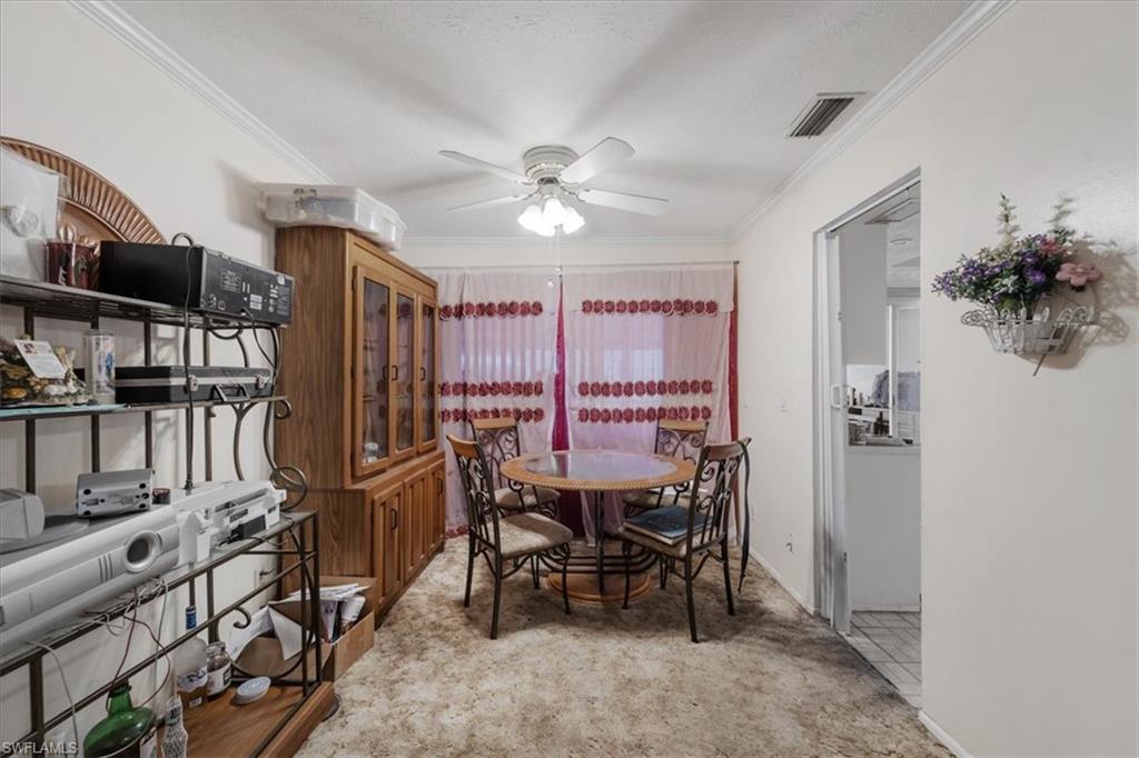 Dining room with crown molding, light carpet, and a ceiling fan