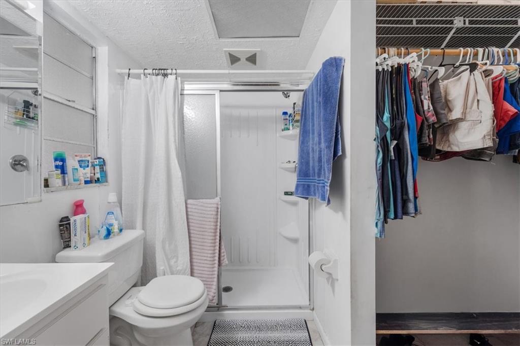 Bathroom with a shower stall, a textured ceiling, vanity, and a spacious closet