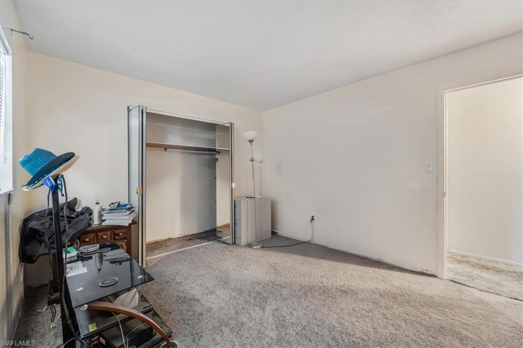 Carpeted bedroom with a closet and a desk