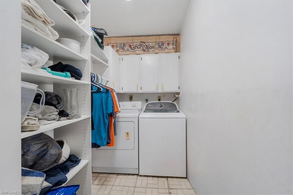 Laundry area featuring cabinet space, washing machine and dryer, and brick patterned flooring