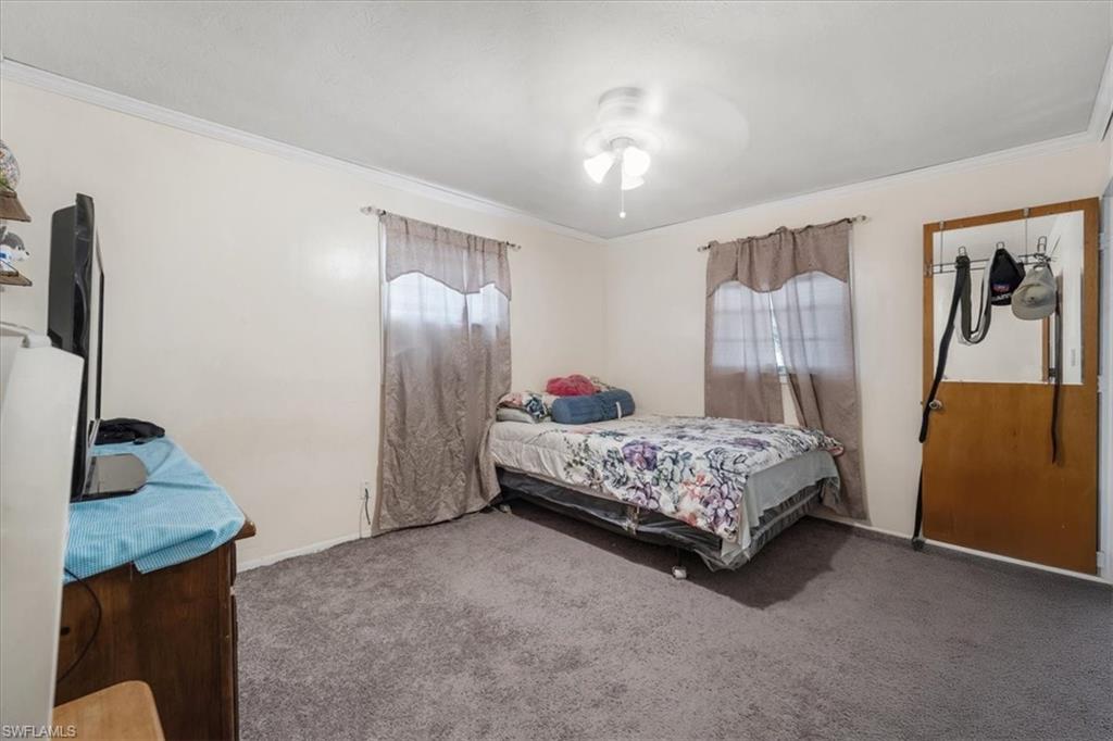 Carpeted bedroom featuring ornamental molding and ceiling fan