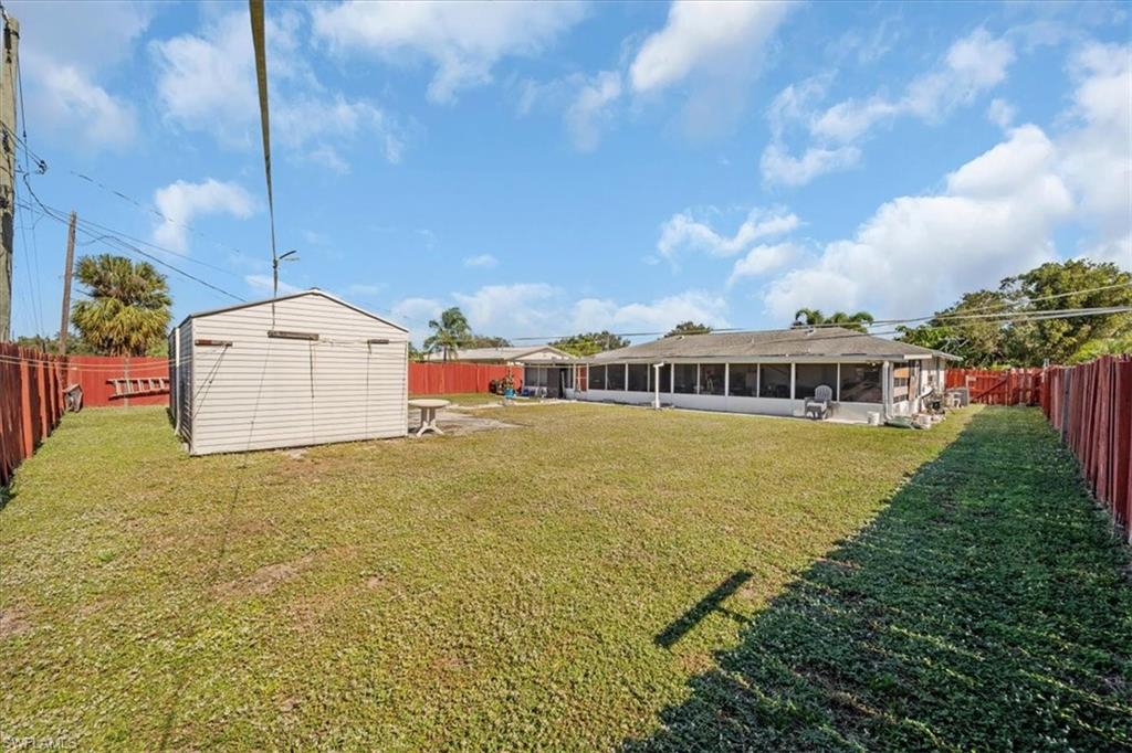 Fenced backyard featuring a sunroom, a patio area, and a shed