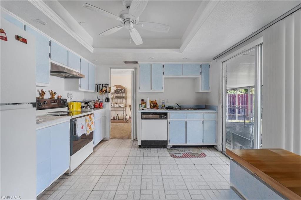 Kitchen featuring white appliances, light countertops, brick patterned floors, ceiling fan, and under cabinet range hood