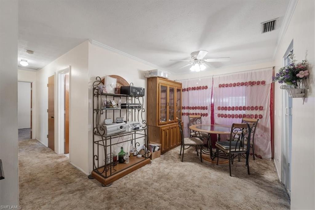 Carpeted dining space featuring crown molding and ceiling fan