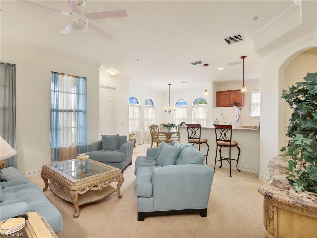 Living area featuring light carpet, ornamental molding, healthy amount of natural light, a chandelier, and ceiling fan