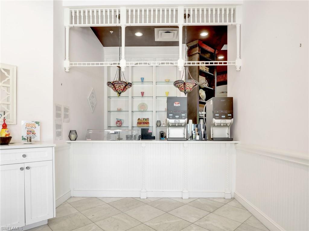 Bar area featuring white cabinetry, light countertops, and a wainscoted wall