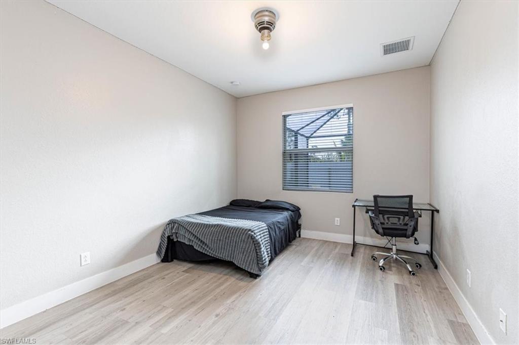 Bedroom with light wood finished floors and a desk