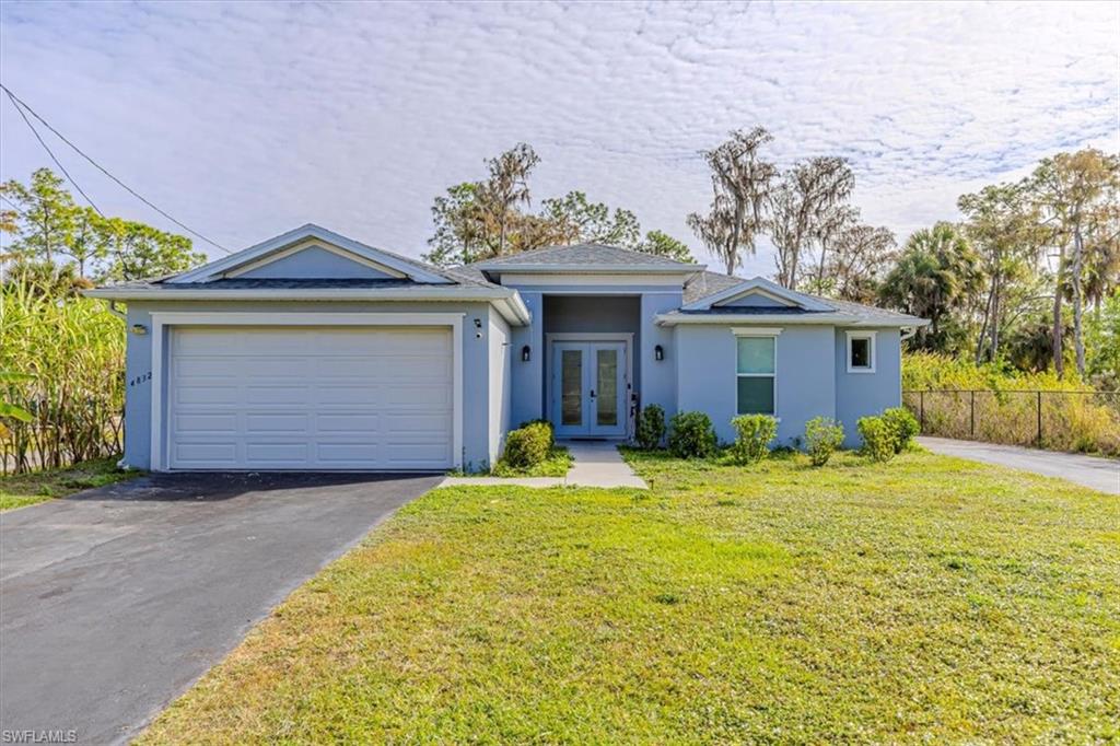 Ranch-style home featuring stucco siding, driveway, french doors, and a garage