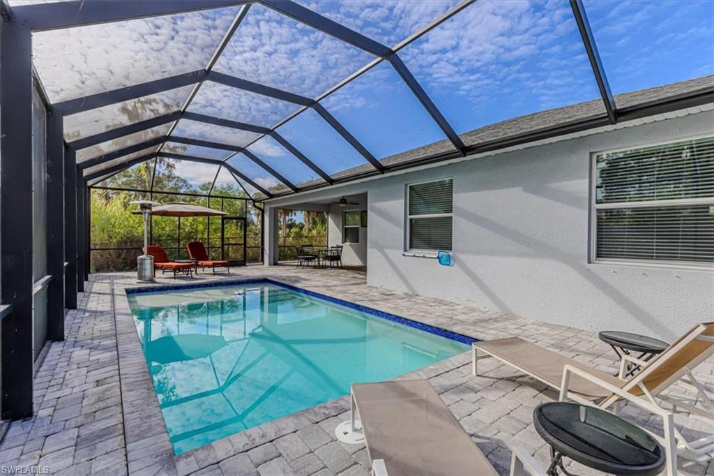 Outdoor pool with a sunroom, a patio area, and a lanai