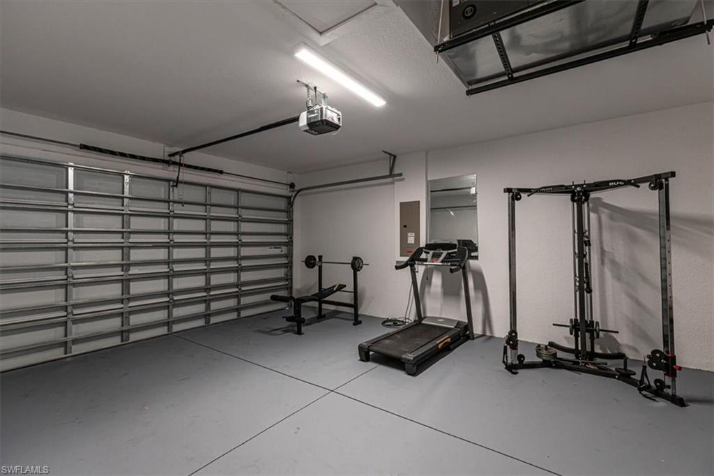 Workout area with a garage, finished concrete floors, and electric panel