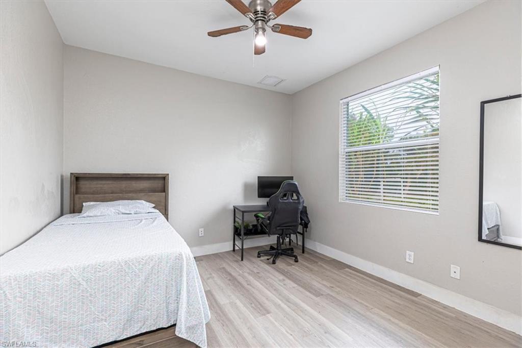 Bedroom with light wood-style floors, a ceiling fan, and a desk