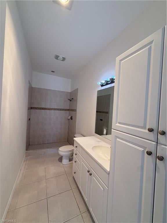 Bathroom featuring a tile shower, vanity, and light tile patterned floors