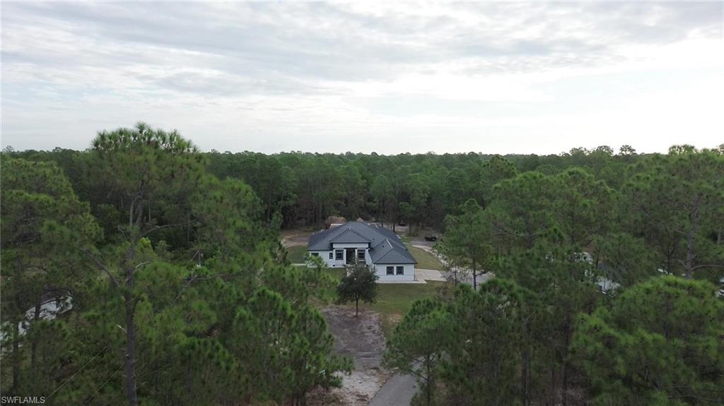 Aerial view of property and surrounding area with a heavily wooded area