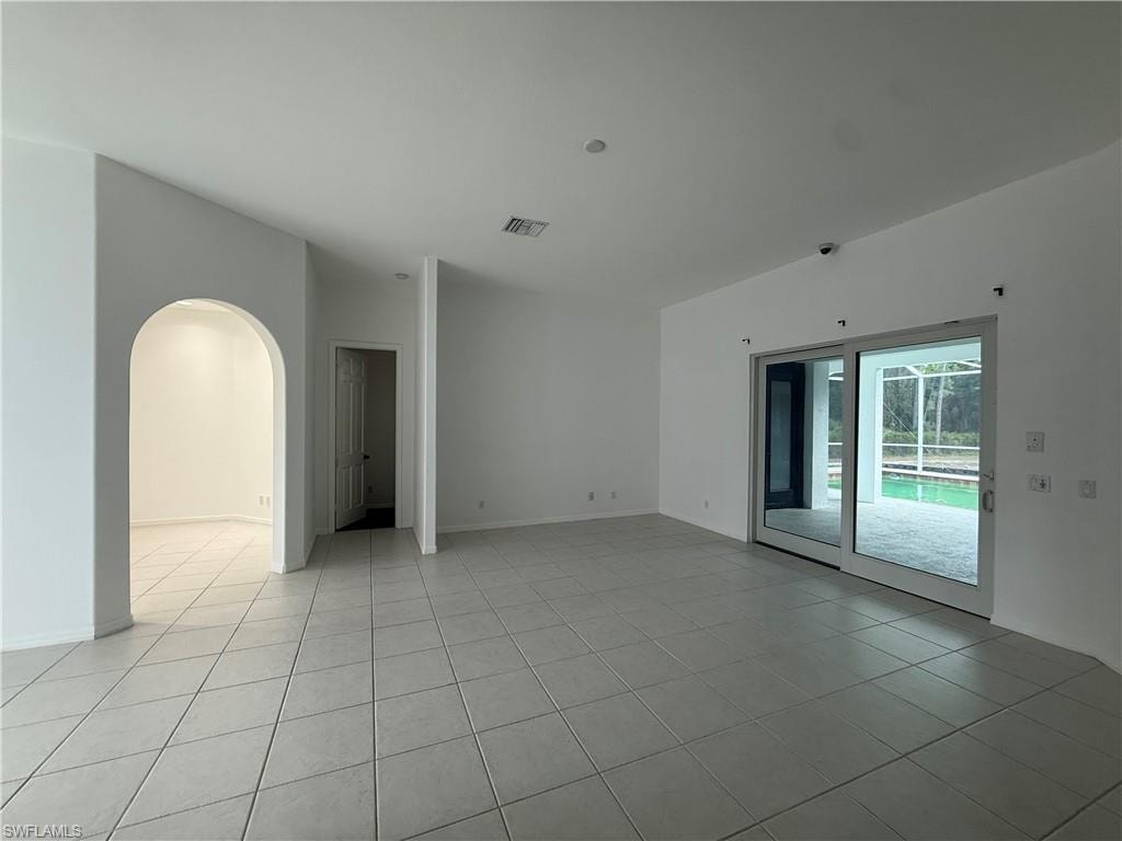 Unfurnished room featuring arched walkways and light tile patterned floors