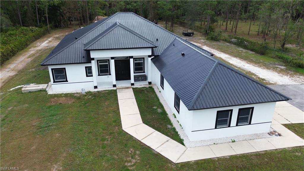 View of front of house featuring stucco siding, a front lawn, and a metal roof