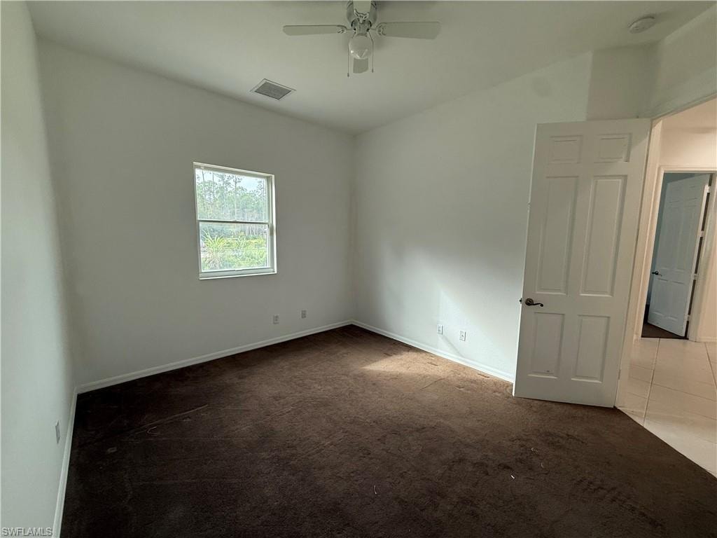 Spare room featuring carpet flooring, ceiling fan, and tile patterned flooring