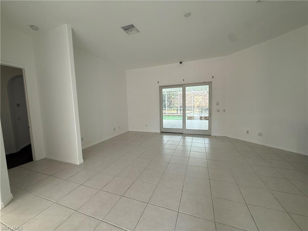 Unfurnished room with light tile patterned floors and arched walkways