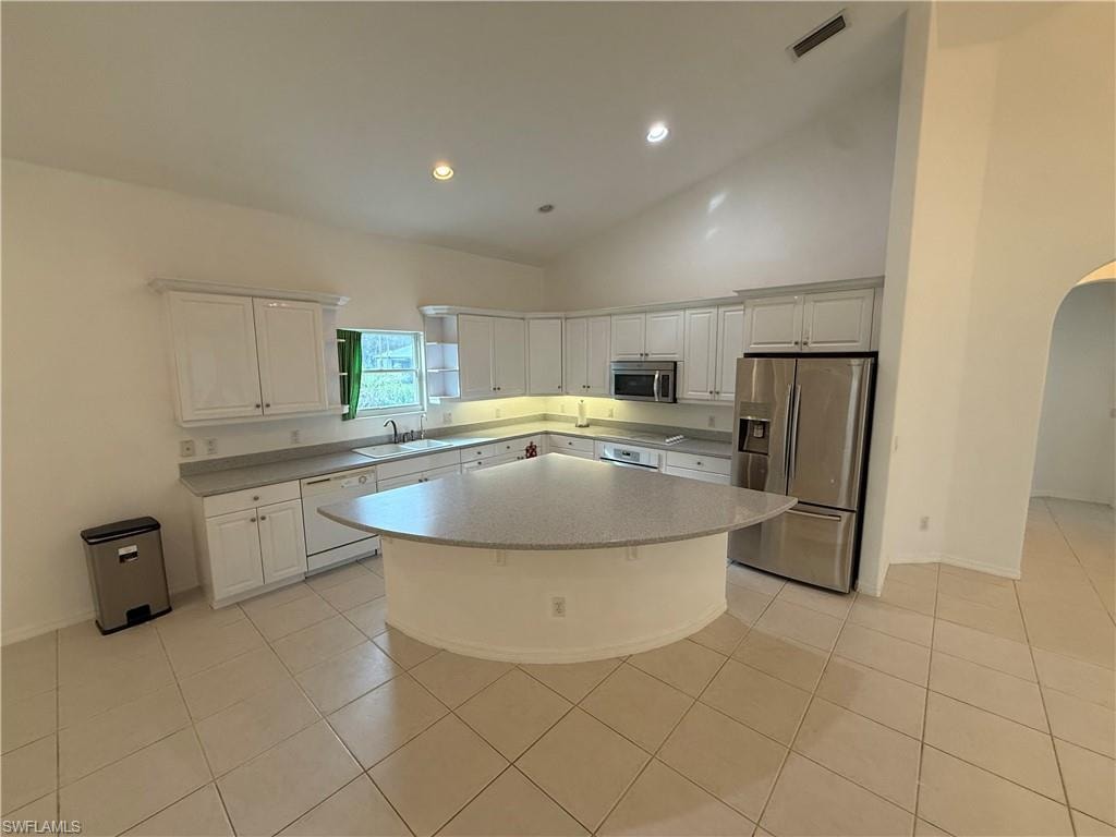 Kitchen with appliances with stainless steel finishes, white cabinets, arched walkways, recessed lighting, and light tile patterned flooring