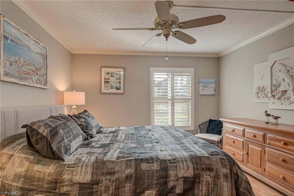 Bedroom featuring crown molding, a textured ceiling, and a ceiling fan