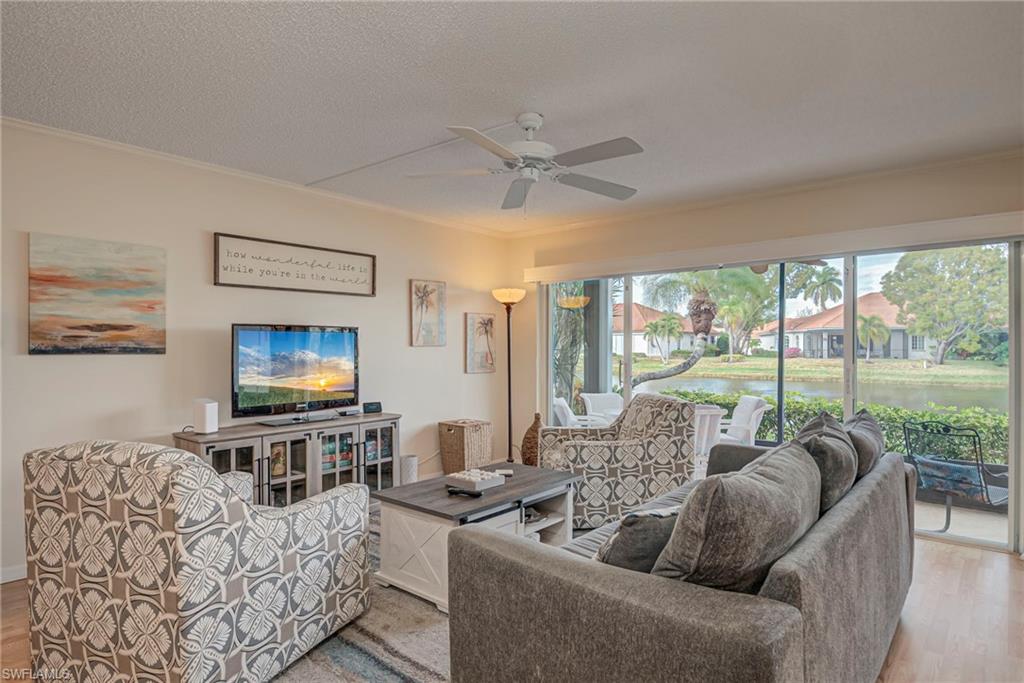 Living area with light wood-type flooring, ceiling fan, a textured ceiling, and crown molding