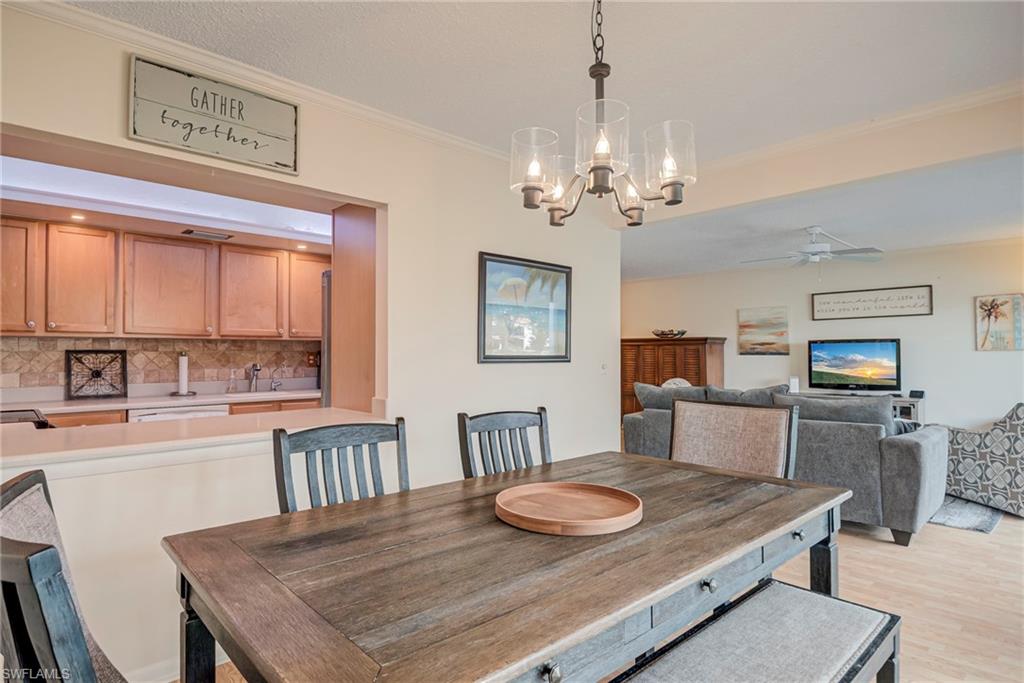 Dining room with crown molding, a chandelier, a ceiling fan, and light wood-type flooring