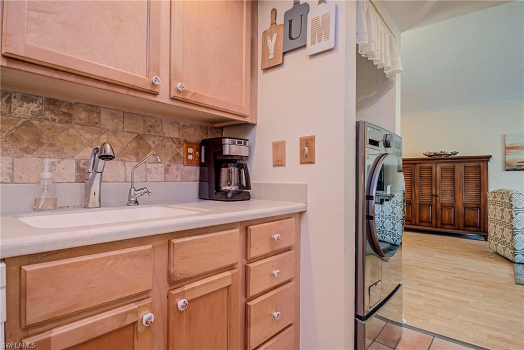 Kitchen with light countertops, washer / dryer, decorative backsplash, and light brown cabinets